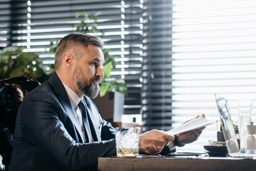 Serious businessman reviewing documents at desk in modern office setting.